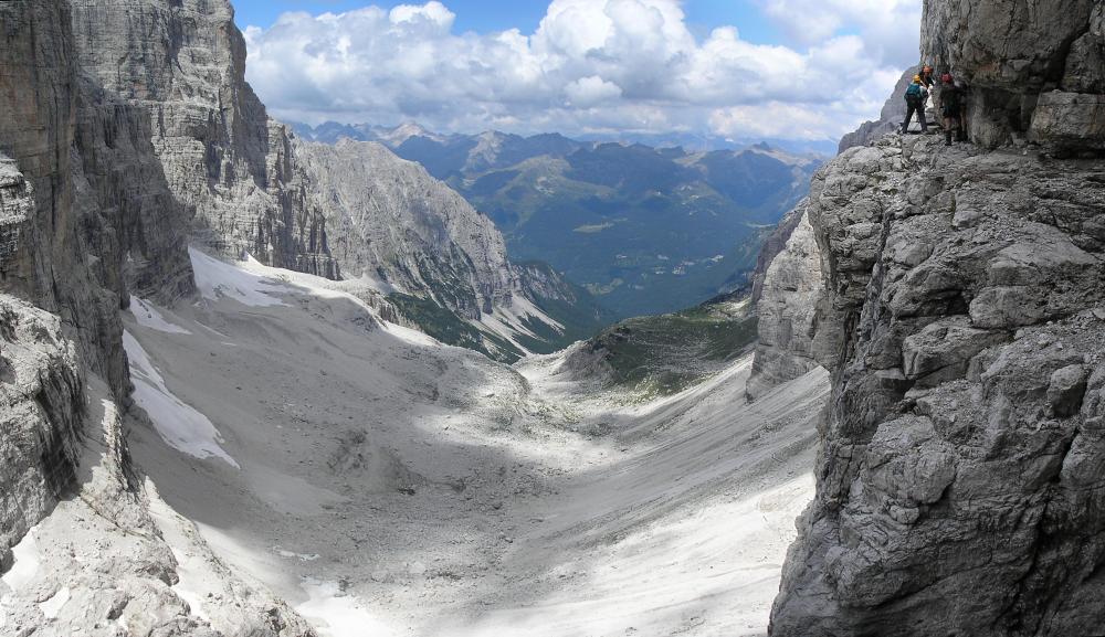 A via ferrata above a snow field in a high and rocky alpine valley