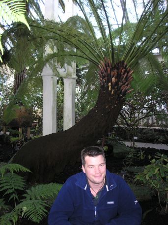 James sat in front of large fern plant in Kew tropical house
