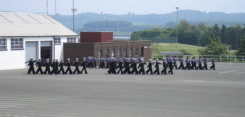 Four divisions, each of 28 people in rows of three, march out onto the parade ground.