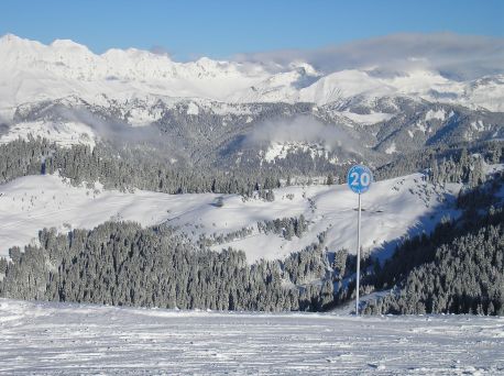 View from a high piste over the adjacent snowcovered mountains, forests and valleys