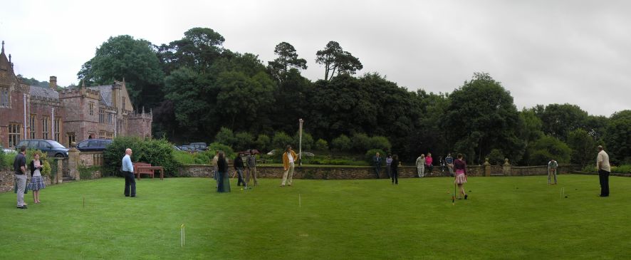 About 8 people playing croquet, with several onlookers